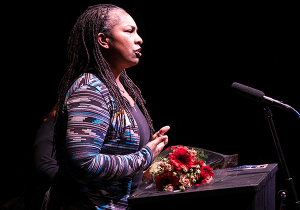 Kimberly Ridgeway, a Black woman with her hair in braids, speaks into a microphone.