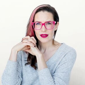 Brunette woman with pink streak in her hair and pink glasses