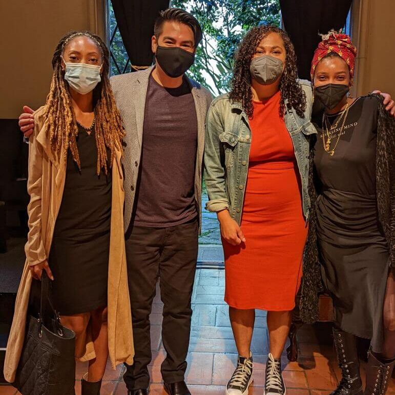 Four masked people stand in a line, posing for the camera.